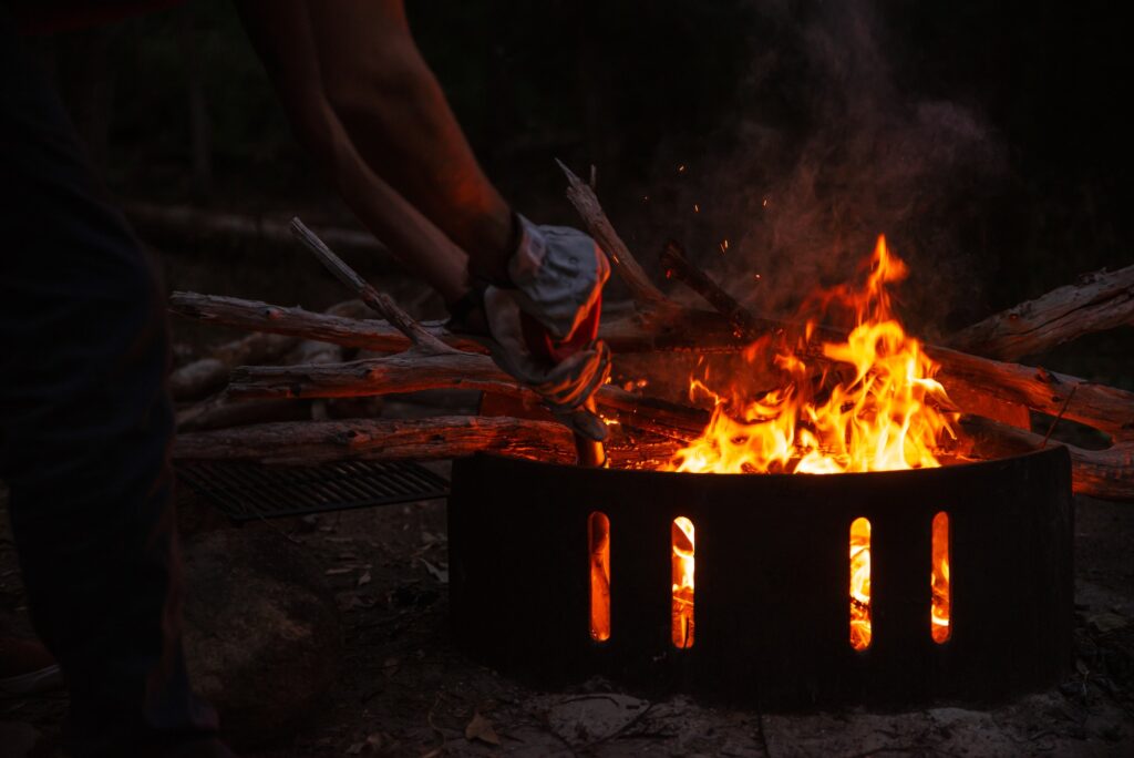 Close Up of Man Hands Working in a Fire Pit in a Camping at Night.Outdoor Concept