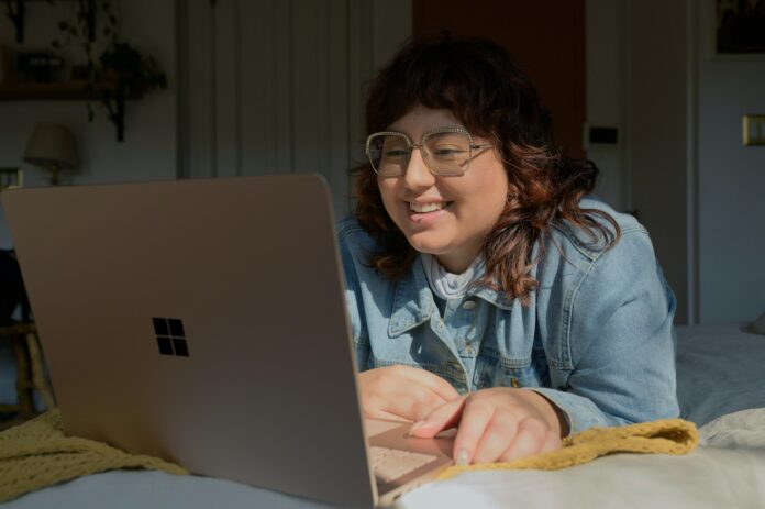 a woman in glasses is looking at a laptop