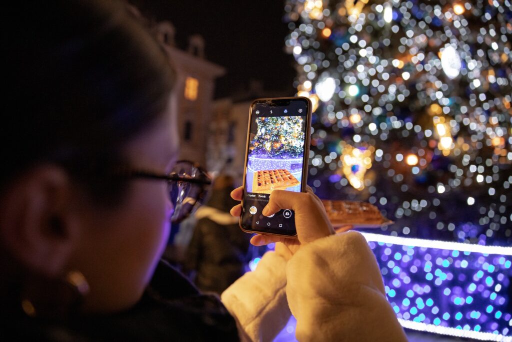 person holding iphone taking photo of lighted christmas tree for a church instagram post example